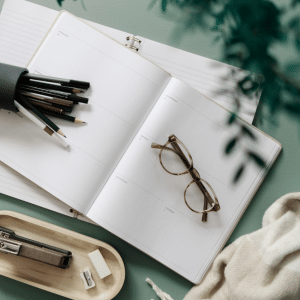 Open weekly planner with pencils and reading glasses on a desk, symbolising readability, clear typography, and accessible design.